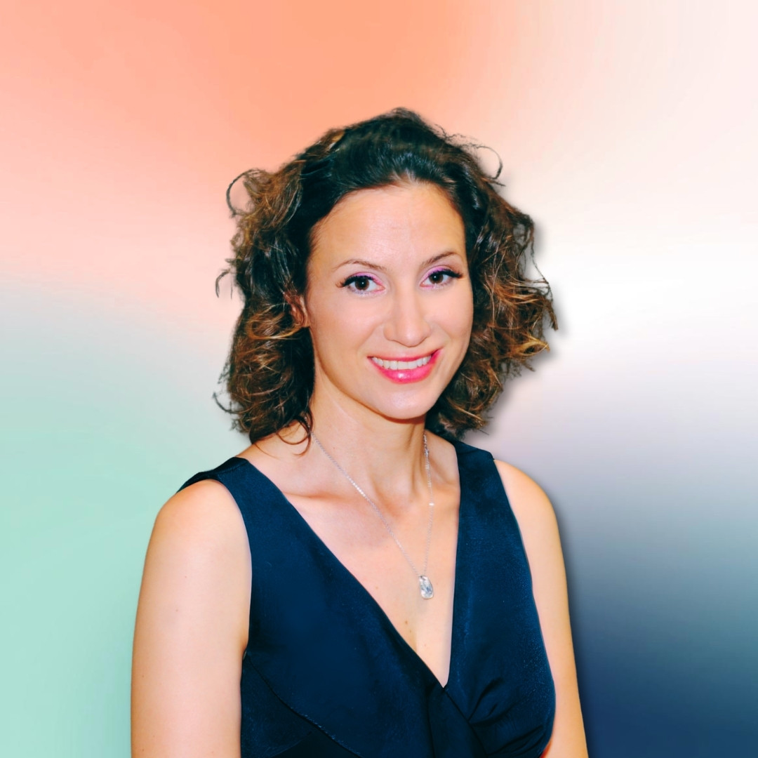 Natalie smiling at the camera in a warm, calm waist-up portrait
