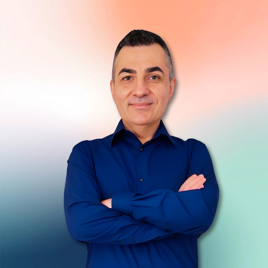 George smiling at the camera with folded arms in a calm, confident portrait